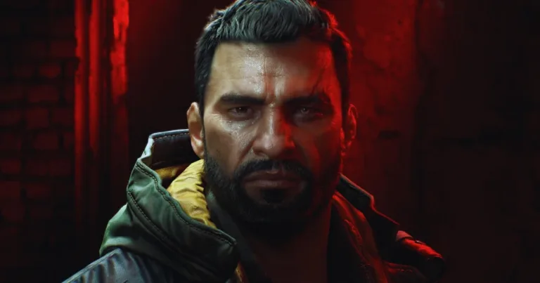 The Beast main character close-up, bruised face and beard, lit by red and black background In-line image
