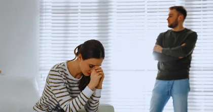 Woman looking down while partner stands in background, retroactive jealousy theme